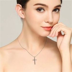 Close-up of a glossy S925 sterling silver cross pendant necklace worn by a model