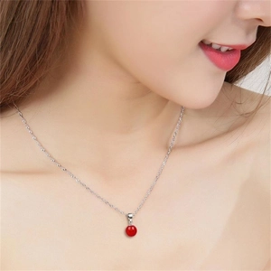 Gros plan d'un collier en argent S925 avec pendentif rond en agate rouge sur le cou d'une femme