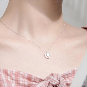 Detail view of a round S925 sterling silver halo necklace pendant worn by a model
