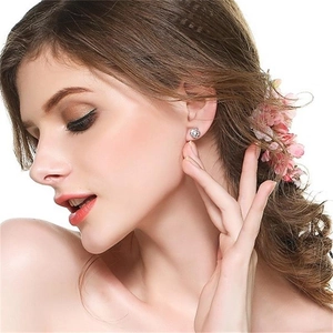 Primo piano dell'orecchino a fiore in argento 925 con zircone lucido indossato dal modello