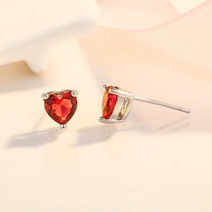 Macro di orecchini a cuore in argento 925 con zirconi rossi in una montatura a tre punte