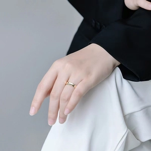 Bague dorée minimaliste pour femme portée au majeur sur une photo de mode