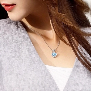 Gros plan d'un collier avec pendentif cœur en pierre bleue porté par un mannequin