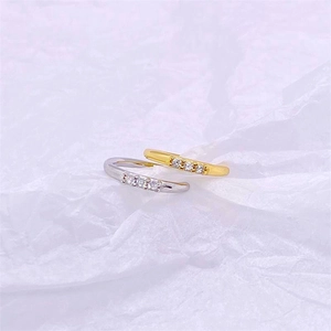 Detail of silver and gold plated rings featuring four prong-set zircon stones on white paper