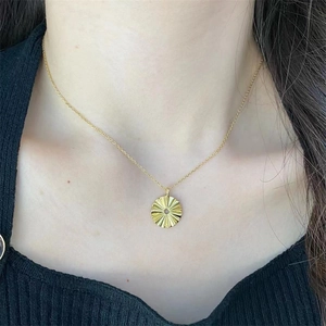 Detail of a golden sunflower necklace showing sunburst texture on a round pendant