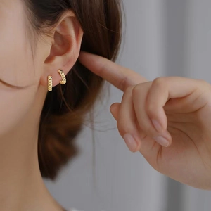 Gros plan de boucles d'oreilles créoles à maillons en argent S925 doré portées par un modèle