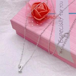 Close-up of silver number 2 pendant on a fine chain in a pink gift box with roses