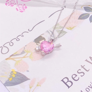 Makroaufnahme von Amors Pfeil Anhänger mit rosa Herzkristall an Silberkette