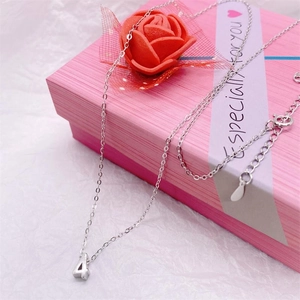 Macro detail of silver number 4 pendant on delicate chain over pink gift box background