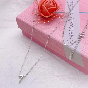 Detailed close-up of a silver number 7 pendant necklace inside a pink gift box