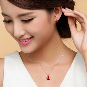 Close-up of minimalist S925 sterling silver necklace and red agate stud earrings on model