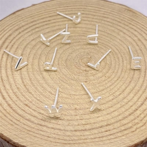 Various S925 sterling silver alphabet stud earrings on natural wood texture base