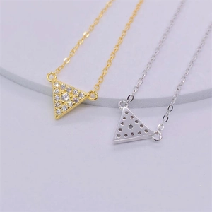 Détail macro de pendentifs triangles géométriques sertis de zircons sur chaînes dorées