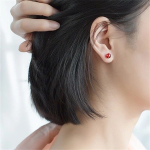 Close-up of minimalist red garnet bead stud earrings on a model showing polished finish