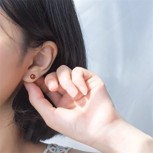 Macro view of natural garnet stud earring on model showing rich red gemstone clarity
