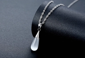 Macro view of a teardrop-shaped cat eye stone pendant on a silver rope chain