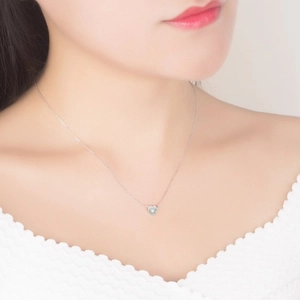 Gros plan du collier coeur en argent S925 avec pierre précieuse blanche sur le cou
