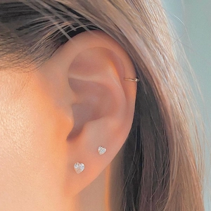 Close-up of S925 sterling silver heart zircon stud earrings and gold ear cuff on a model