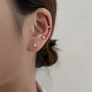 Close-up of three different sizes of S925 silver heart-shaped zircon earrings on ear