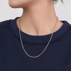 Silver link chain necklace detail on a model wearing a dark navy blue sweater