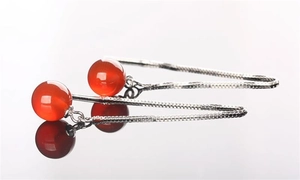 Macro shot of long S925 sterling silver tassel earrings with red agate beads and reflections