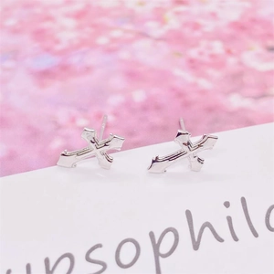 Gros plan de boucles d'oreilles croix minimalistes en argent sterling S925 sur papier