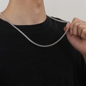 Macro shot of a sleek S925 sterling silver curb chain held by a hand on a black t-shirt