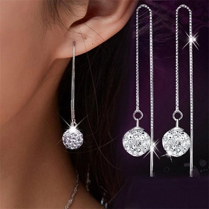 Macro detail of long S925 sterling silver drop earrings with sparkling disco ball charms