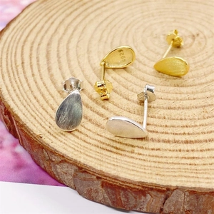 Macro detail of brushed S925 sterling silver waterdrop earrings in gold and silver finish