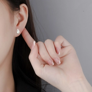 Minimalist S925 sterling silver teardrop studs with matte finish worn on ear lobe