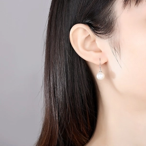 Classic S925 sterling silver pearl drop earrings worn by a model in a side profile view