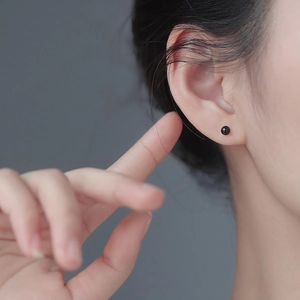 Close-up of minimalist S925 sterling silver black onyx round stud earring worn on ear