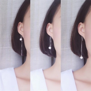 Detail showing long S925 sterling silver chain earrings with white round pearls on model