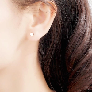 Close-up of a minimalist S925 sterling silver barbell stud earring on a model's ear