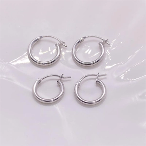 Detailed macro view of four polished S925 sterling silver hoop earrings on white fabric