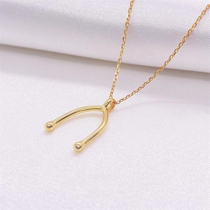 Elegant gold wishbone pendant necklace on white silk background with minimalist chain