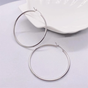 Polished S925 sterling silver hoop earrings displayed on a white shell-shaped tray