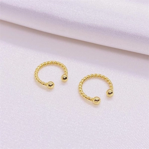 Boucles d'oreilles S925 argent torsadé doré posées sur un tissu en soie violette