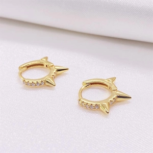 Macro shot of gold-plated punk hoop earrings with cubic zirconia and conical spikes