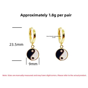 Close-up of gold S925 sterling silver huggie earrings with black and white yin yang charms