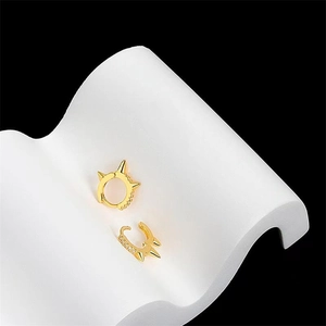 Detailed view of punk style gold hoop earrings with sharp spikes and pavé zircons