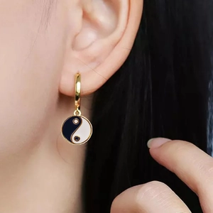 Close-up of S925 silver yin yang drop earrings worn on ear with gold hoop detail