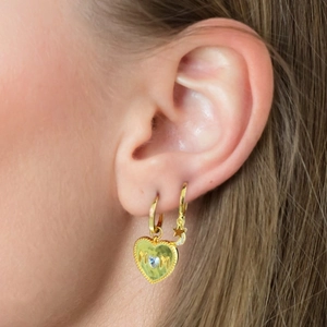 Detail of gold heart MOM earring and star moon pendants on a model with warm lighting