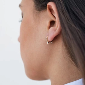 Detail of gold hoop earring with cone studs and pavé crystals on ear