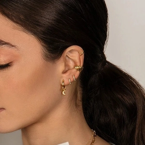 Detailed view of layered gold crescent moon earrings and sparkling cubic zirconia ear cuffs