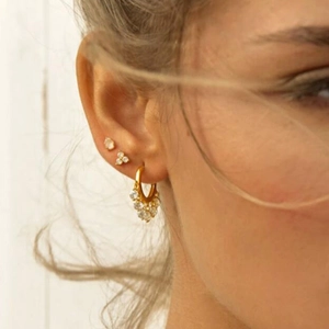 Close-up of elegant gold S925 silver stud earrings with zirconia stones worn by a model