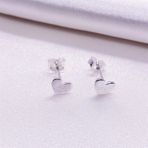 Minimalist S925 sterling silver heart-shaped stud earrings on soft silk fabric