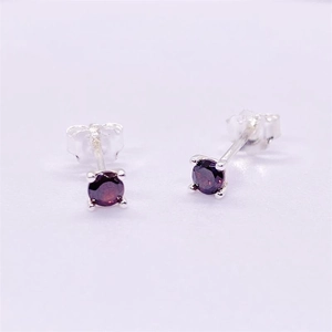 Detailed view of 925 sterling silver stud earrings with red cubic zirconia four-prong setting
