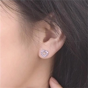 Detail view of heart-shaped silver stud earrings with purple micro-pave crystals on ear