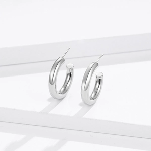 Polished silver C-shaped hollow hoop earrings on minimalist geometric white background